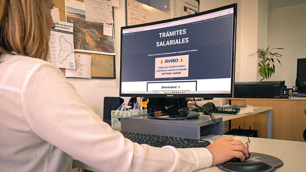 mujer sentada delante de una computadora observando la pantalla con la leyenda trámites salariales en el encabezado